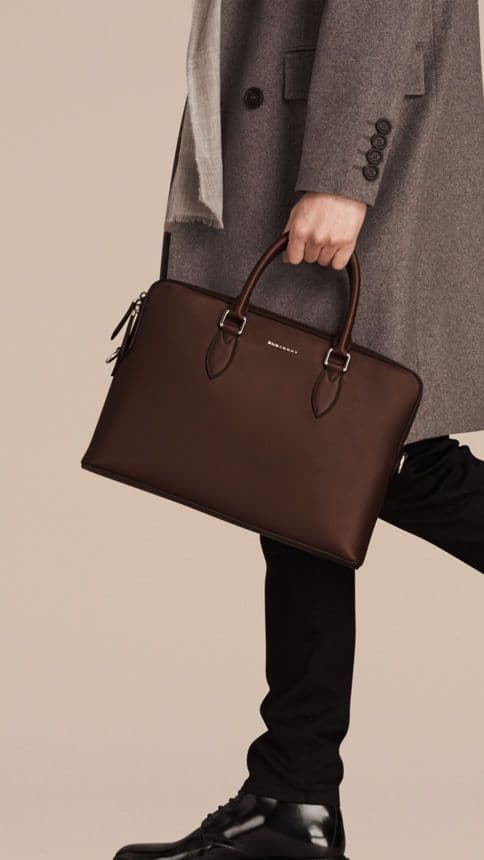 a man holding a leather bag walking