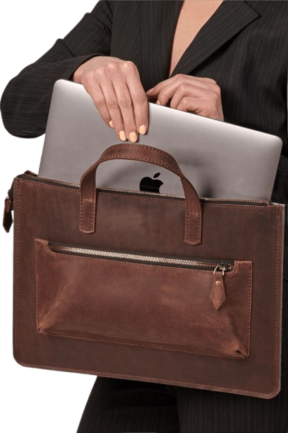a lady putting a laptop into a brown leather laptop bag